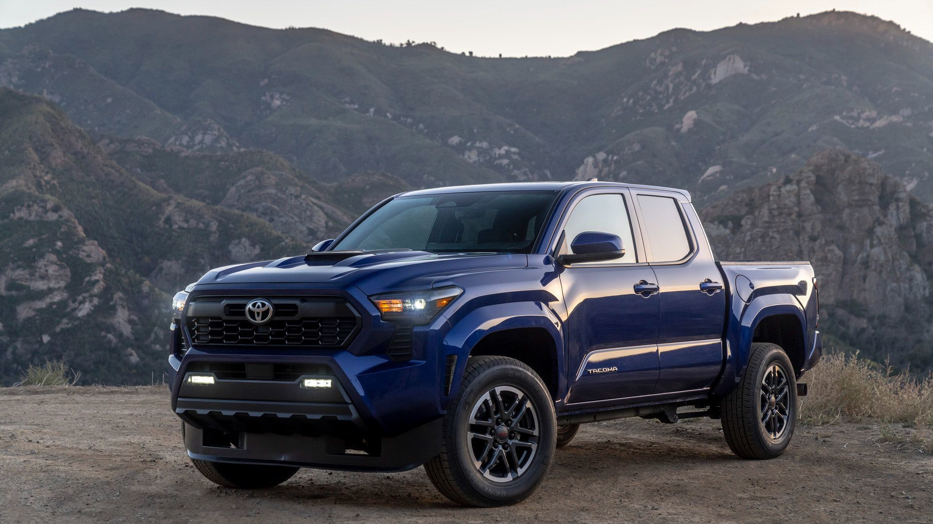 2026 Toyota Tacoma - Front three-quarter view of a blue TRD Sport model parked with mountains in the background - Goderich Toyota - New car dealership in Goderich, Ontario