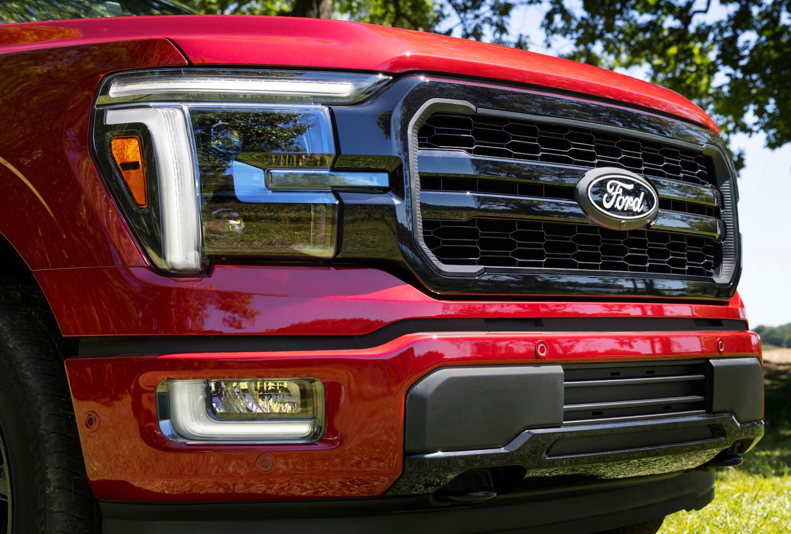 2026 Ford F-150 - close-up of the front grille and headlight on a red 2026 Ford F-150 Lariat - Bayfield Ford - New car dealership in Barrie, Ontario