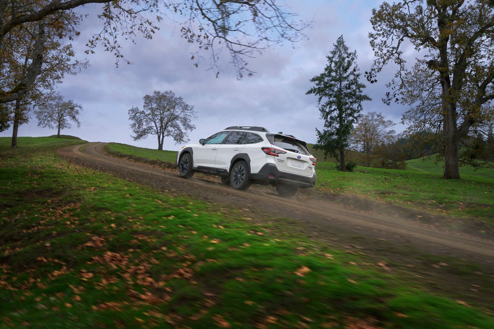 Subaru Outback - White Subaru Outback driving up a dirt hill - AutoPark Barrie - Pre-owned car dealership in Innisfil, Ontario
