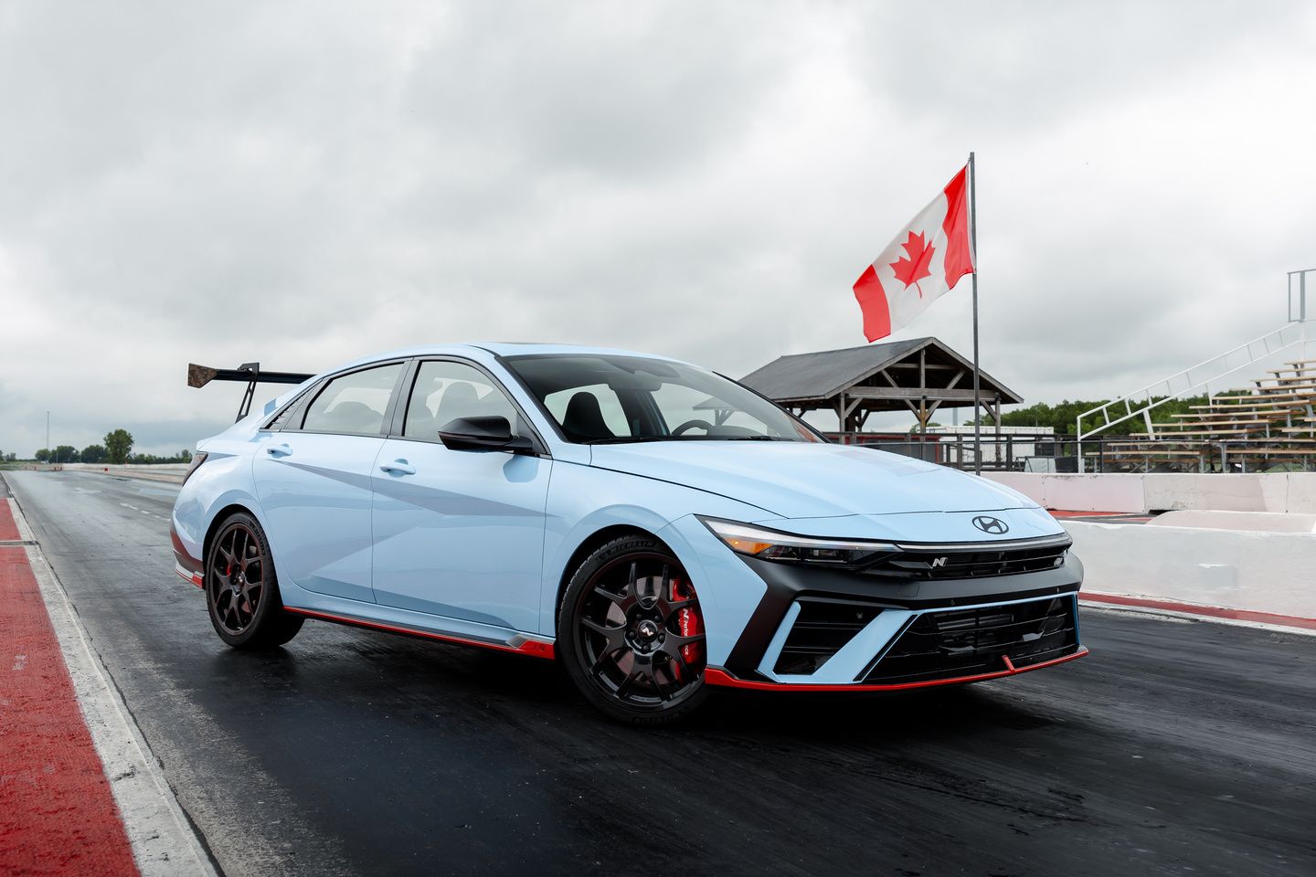 2026 Hyundai Elantra N TCR - front angle view of a Performance Blue sports sedan on a race track - Woodstock Hyundai - New car dealership in Woodstock, Ontario
