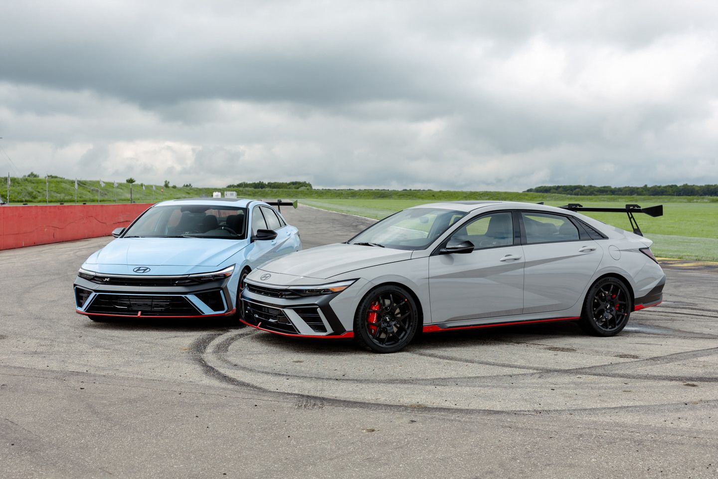 2026 Hyundai Elantra N TCR - view of Performance Blue and Grey sports sedans parked on a race track - Woodstock Hyundai - New car dealership in Woodstock, Ontario