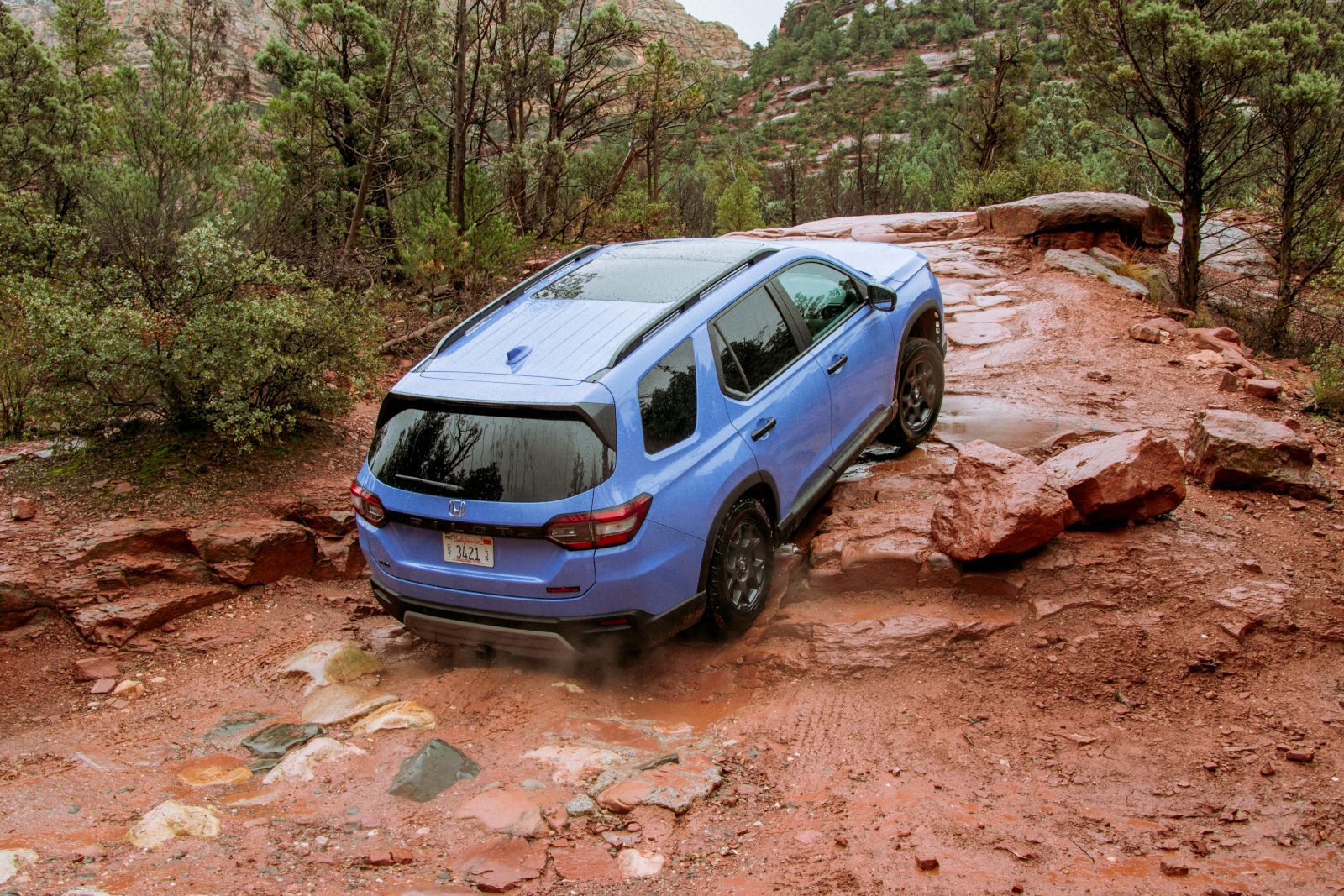 2026 Honda Pilot - a blue 2026 Honda Pilot TrailSport driving over red rocky terrain - Humberview Group - New car dealerships in Ontario