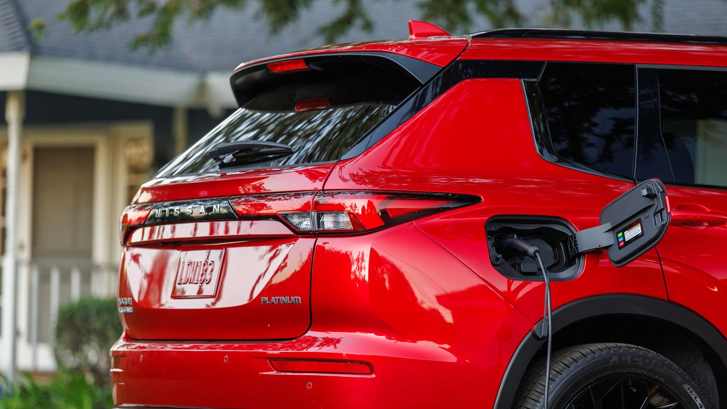 2027 Nissan Rogue Plug-in Hybrid - rear view of a red 2027 Nissan Rogue Plug-in Hybrid charging in a driveway - Humberview Group - New car dealerships in Ontario
