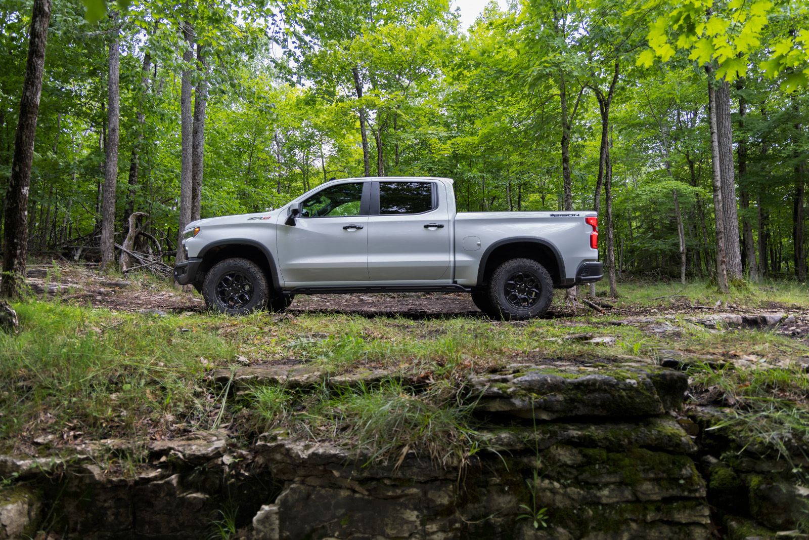 2026 Chevrolet Silverado ZR2 Bison - side view of a silver truck parked in the woods.