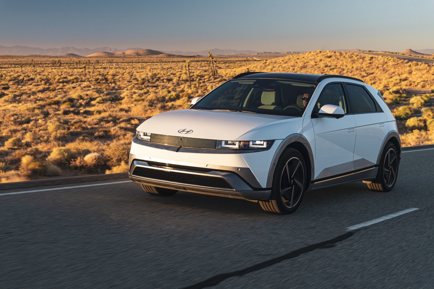 2026 Hyundai IONIQ 5 - a white 2026 Hyundai IONIQ 5 driving on a desert road - Woodstock Hyundai - New car dealership in Woodstock, Ontario