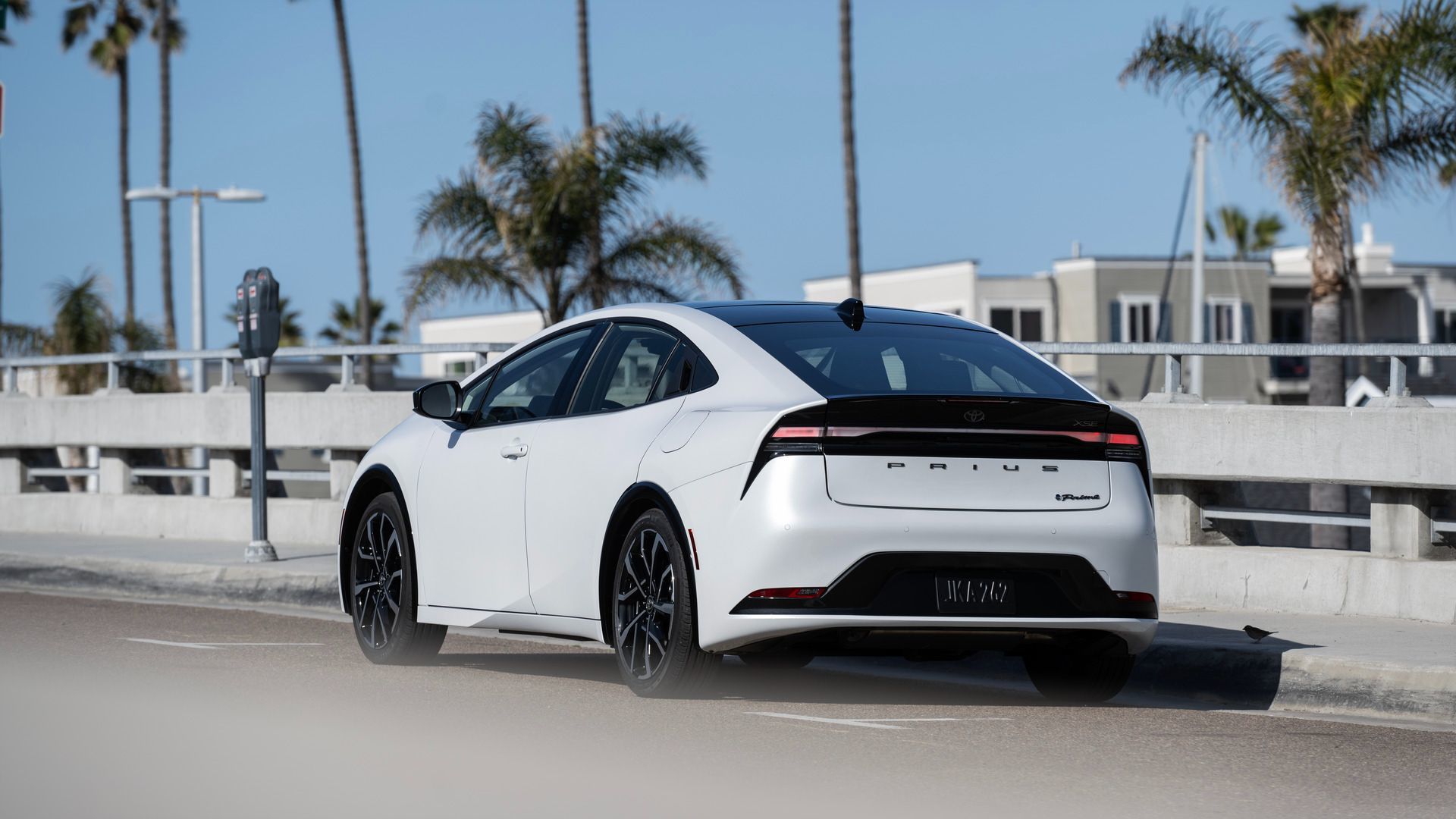 2026 Toyota Prius PHEV - rear view of a white 2026 Toyota Prius PHEV driving on a sunny road - Oakville Toyota - New car dealership in Oakville, Ontario