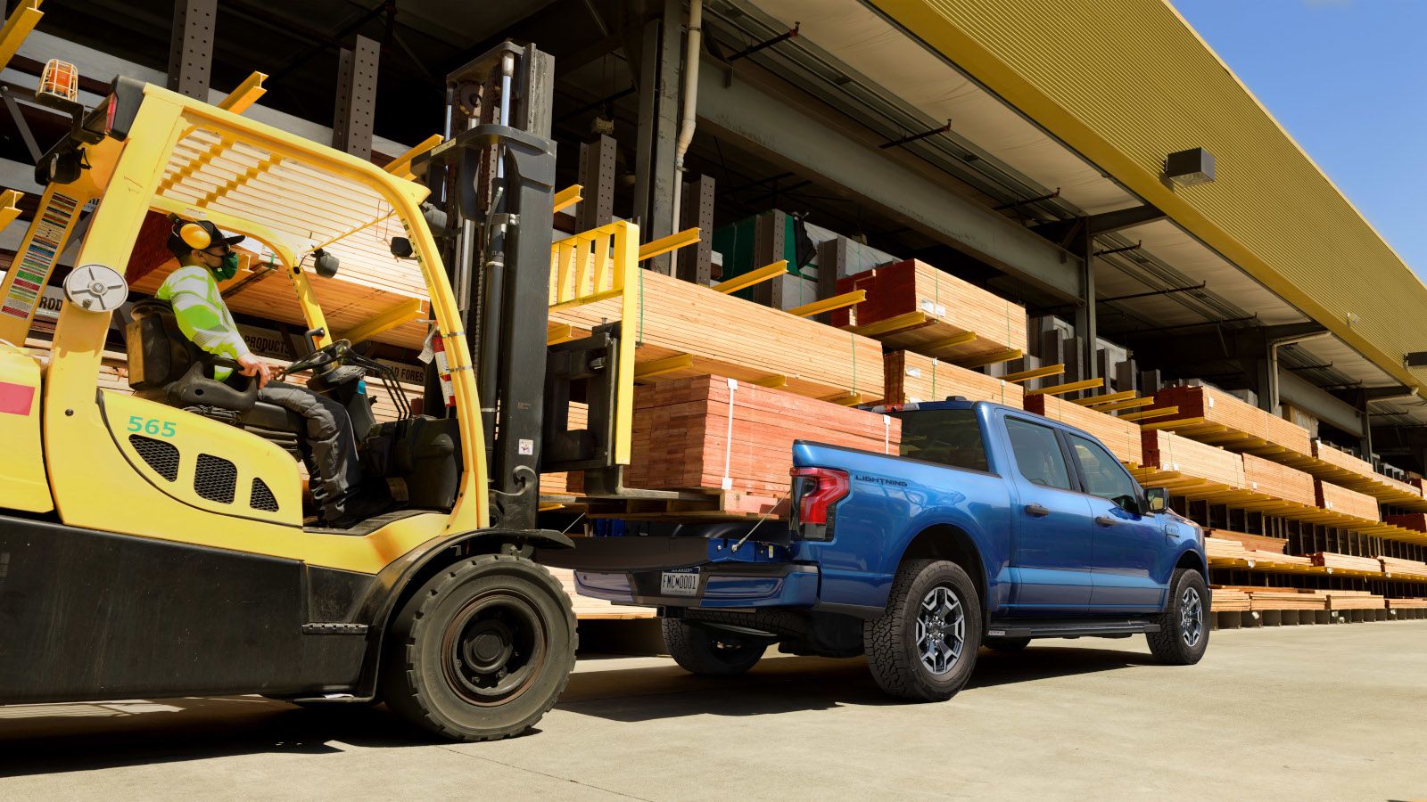 2026 Ford F-150 Lightning - a blue Ford F-150 Lightning being loaded with lumber by a forklift - Mayfield Ford - New car dealership in Brampton, Ontario