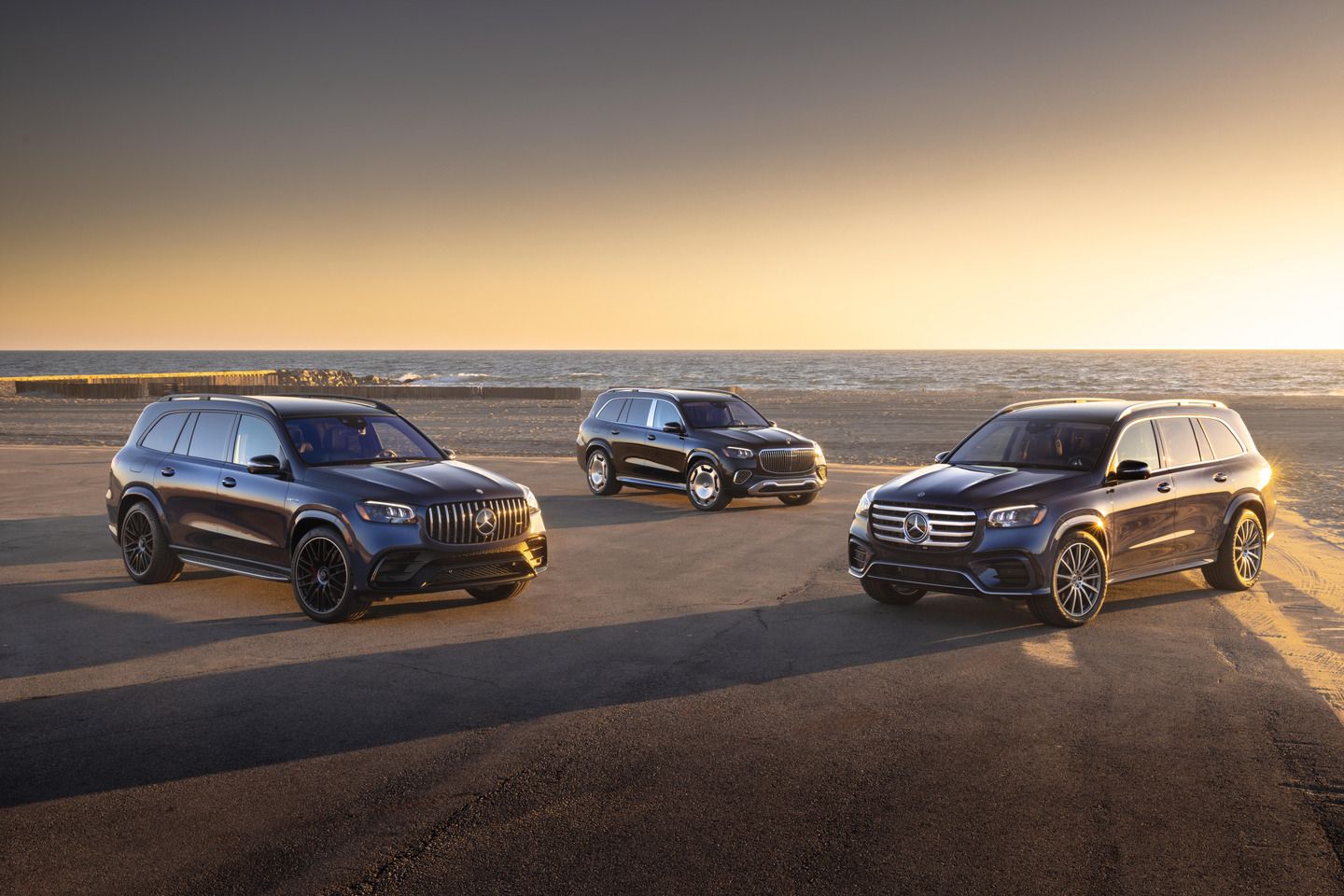 2026 Mercedes-Benz GLS - group shot of three 2026 Mercedes-Benz GLS models parked on a sandy beach at sunset - Mercedes-Benz Brampton - New car dealership in Brampton, Ontario