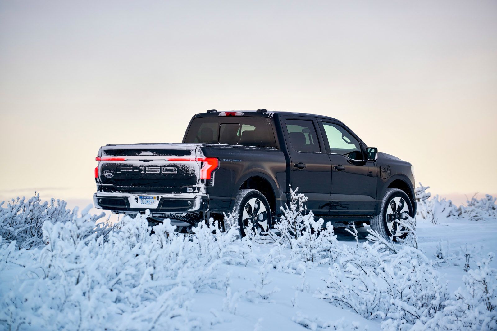 2026 Ford F-150 Lightning - rear view of a black Ford F-150 Lightning driving in deep snow - Humberview Group - New car dealerships in Ontario