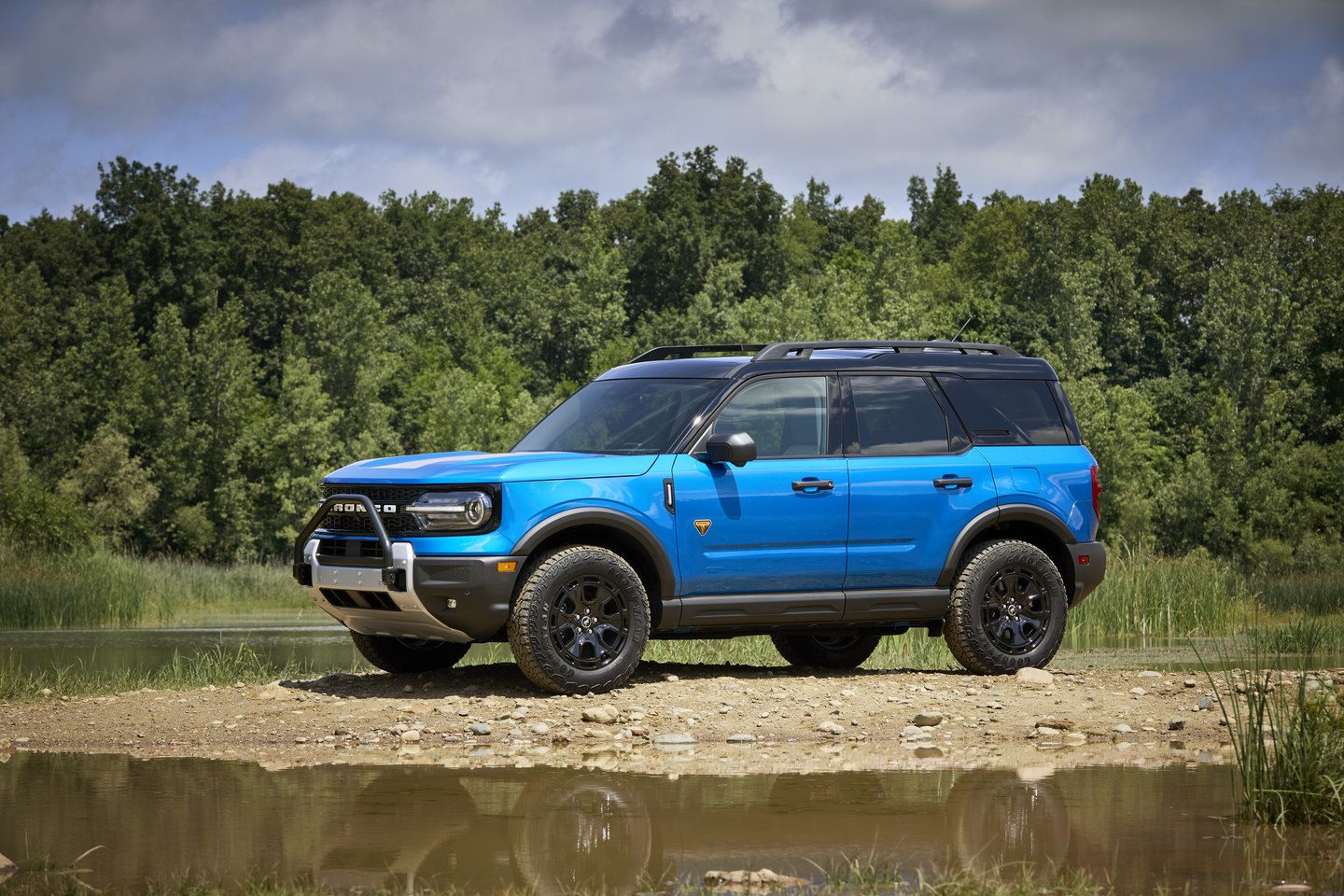 2026 Ford Bronco Sport - a blue 2026 Ford Bronco Sport parked on a dirt bank near a pond - Bayfield Ford - New car dealership in Barrie, Ontario