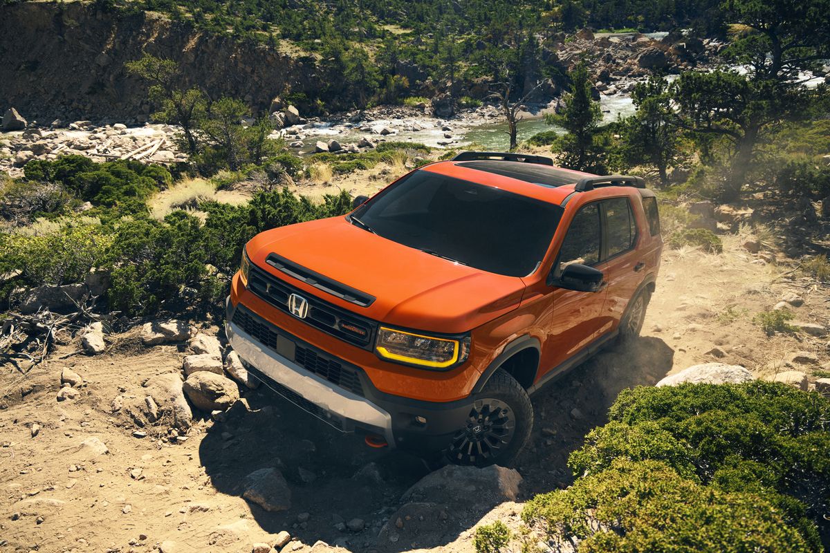2026 Honda Passport TrailSport - high-angle front view of an orange 2026 Honda Passport TrailSport crawling over rocks - Goderich Honda - New car dealership in Goderich, Ontario