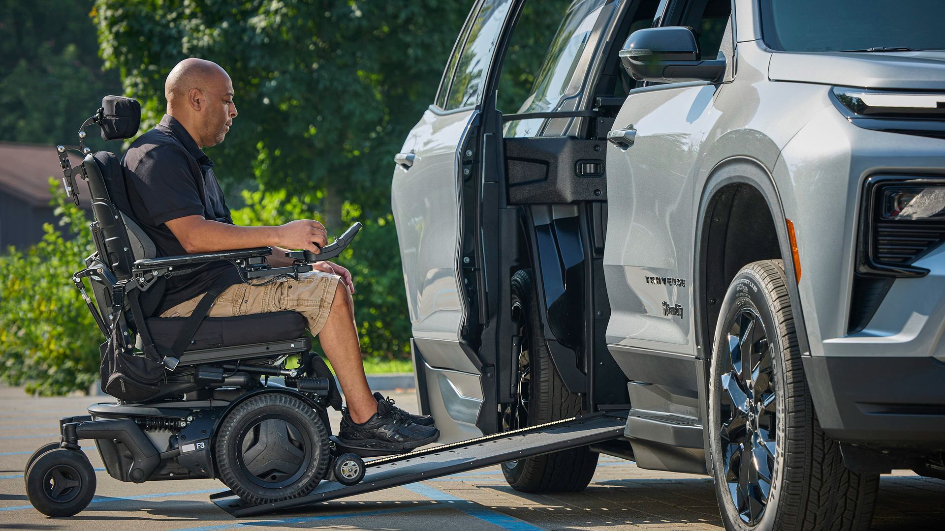 2026 Chevrolet Traverse - side view of a person in a power wheelchair using the side entry ramp on a silver 2026 Chevrolet Traverse - Courtland Mobility - Accessible vehicle dealership in Burlington, Ontario