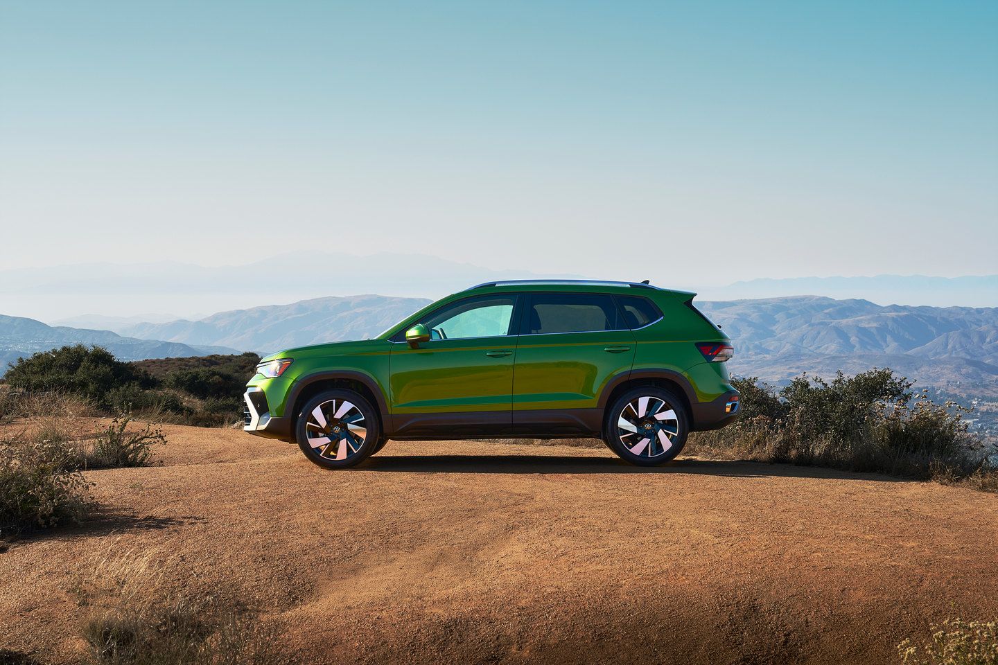 2026 Volkswagen Taos - a side profile view of a green 2026 Volkswagen Taos parked on a dirt path overlooking mountains - Humberview Group - New car dealerships in Ontario