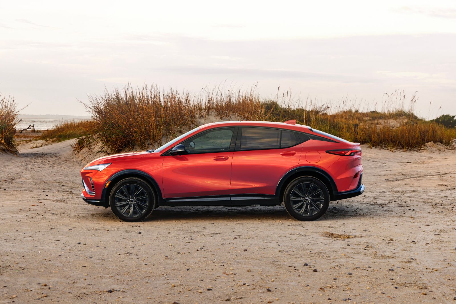 2026 Buick Envista - side profile view of a red 2026 Buick Envista Sport Touring parked on a sandy beach - Humberview Chevrolet, Buick, GMC - New car dealership in Toronto, Ontario