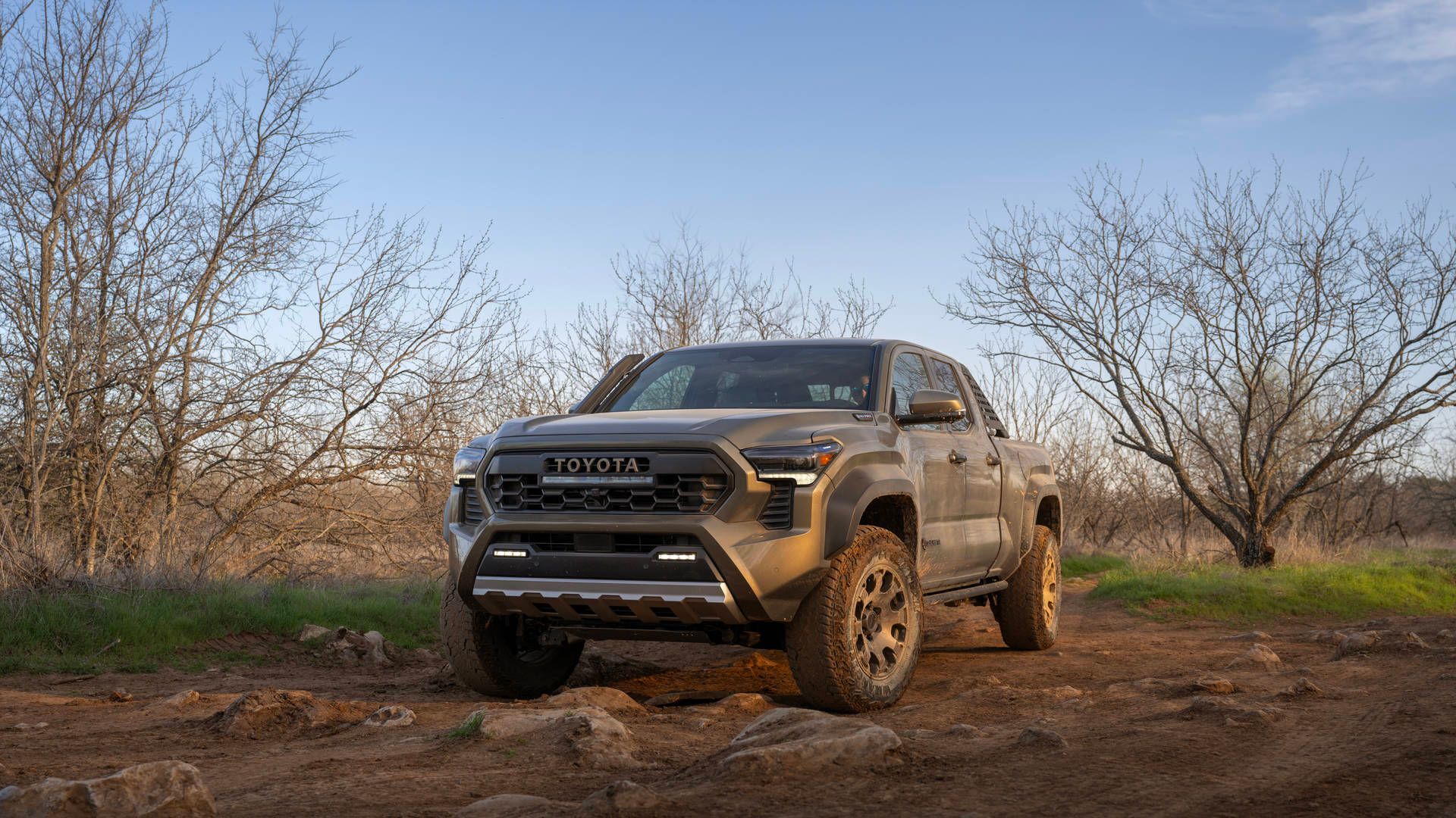 2026 Toyota Tacoma Trailhunter - a bronze 2026 Toyota Tacoma Trailhunter off-roading on a rocky dirt path - Orangeville Toyota - Toyota new car dealership in Orangeville, Ontario