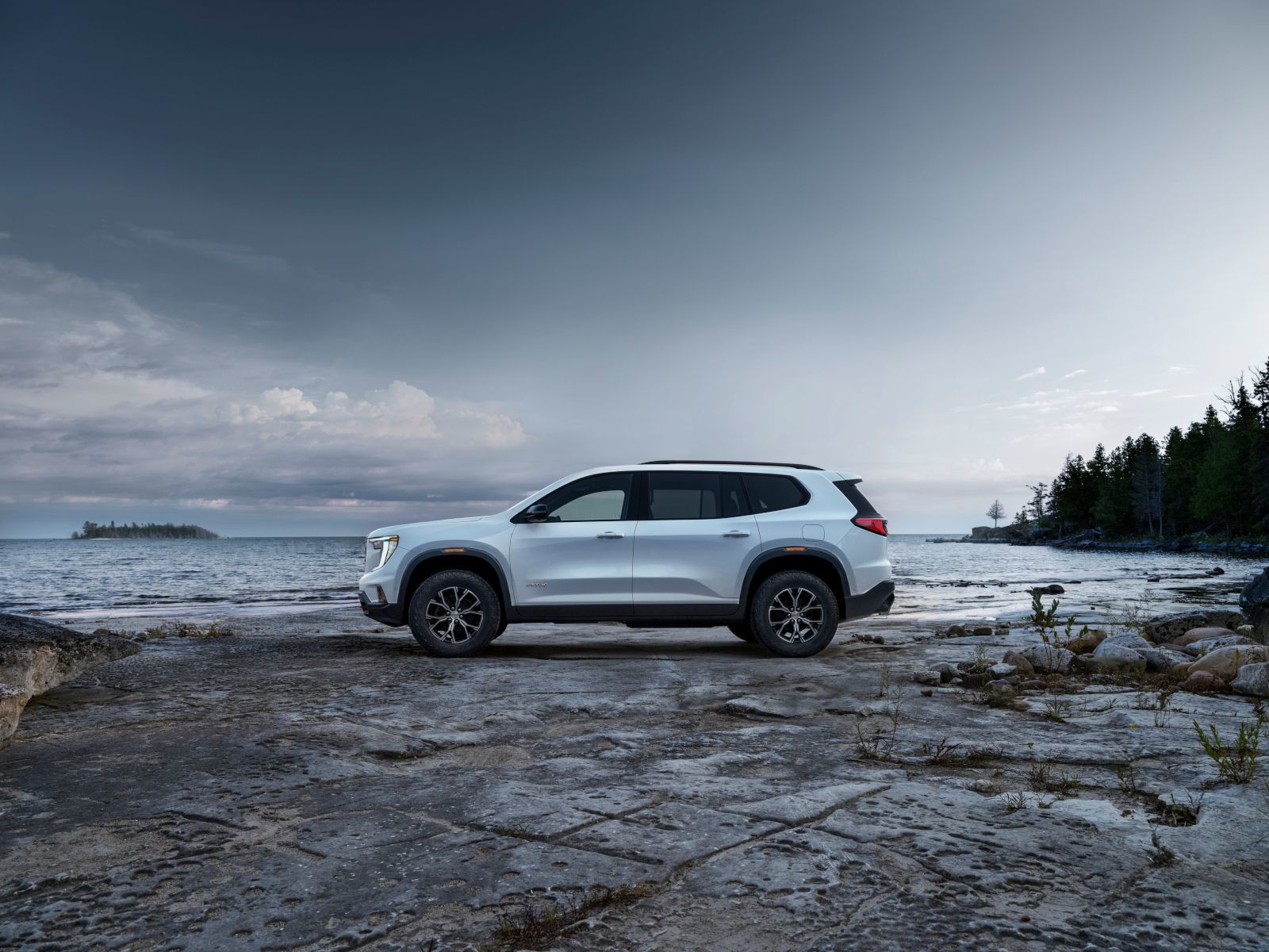 2026 GMC Acadia AT4 - side profile of a white GMC Acadia AT4 parked on a rocky shoreline - City Chevrolet, Buick, GMC - GMC car dealership in Toronto, Ontario