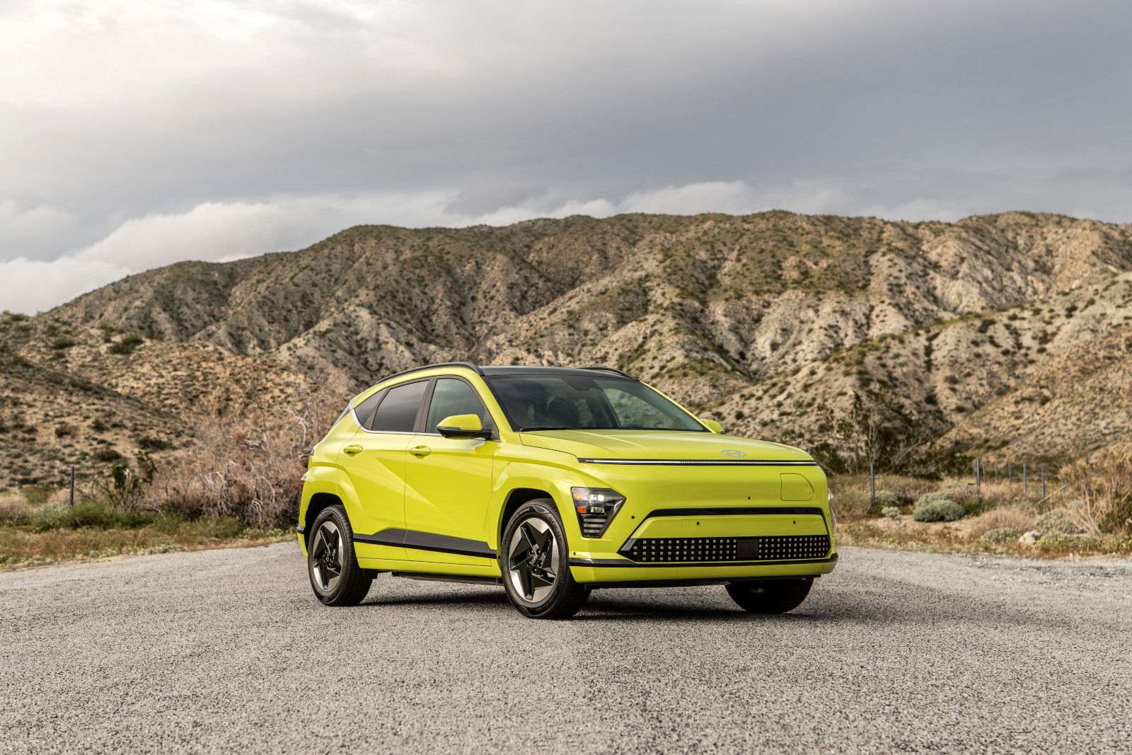 2026 Hyundai Kona Electric - a lime green 2026 Hyundai Kona Electric parked on a gravel path with mountains in the background - Humberview Group - New car dealerships in Ontario