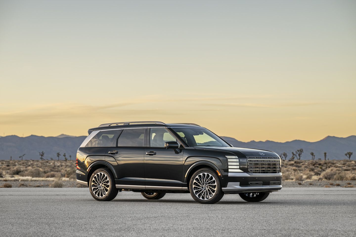 2026 Hyundai Palisade - a dark green 2026 Hyundai Palisade Hybrid Calligraphy parked on a flat desert landscape at dusk - Humberview Group - New car dealerships in Ontario