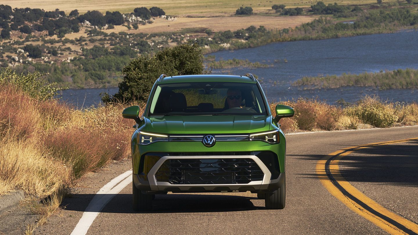 2026 Volkswagen Taos - direct front view of a bright green 2026 Volkswagen Taos driving toward the camera on a lakeside road - Volkswagen Mid-Town Toronto - New car dealership in Toronto, Ontario