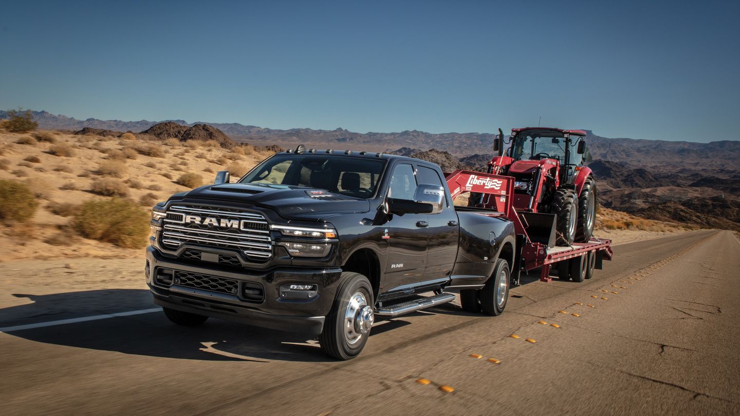 2026 Ram 3500 Laramie - a black 2026 Ram 3500 Laramie dually towing a red tractor on a flatbed trailer - Humberview Group - New car dealerships in Ontario