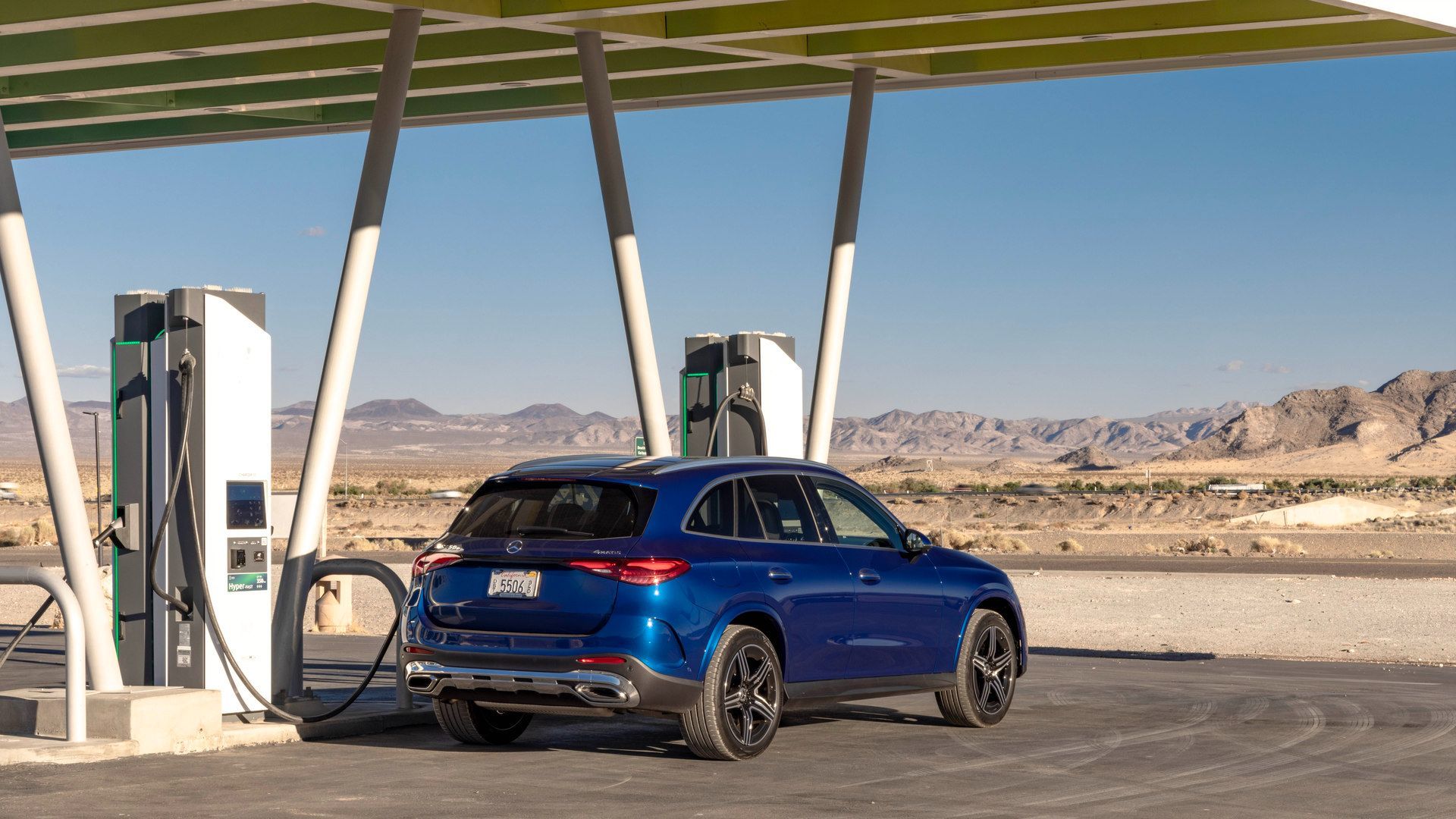 2026 Mercedes-Benz GLC 350e - rear three-quarter view of a blue 2026 Mercedes-Benz GLC 350e plug-in hybrid at an EV charging station in a desert landscape - Mercedes-Benz Brampton - New car dealership in Brampton, Ontario