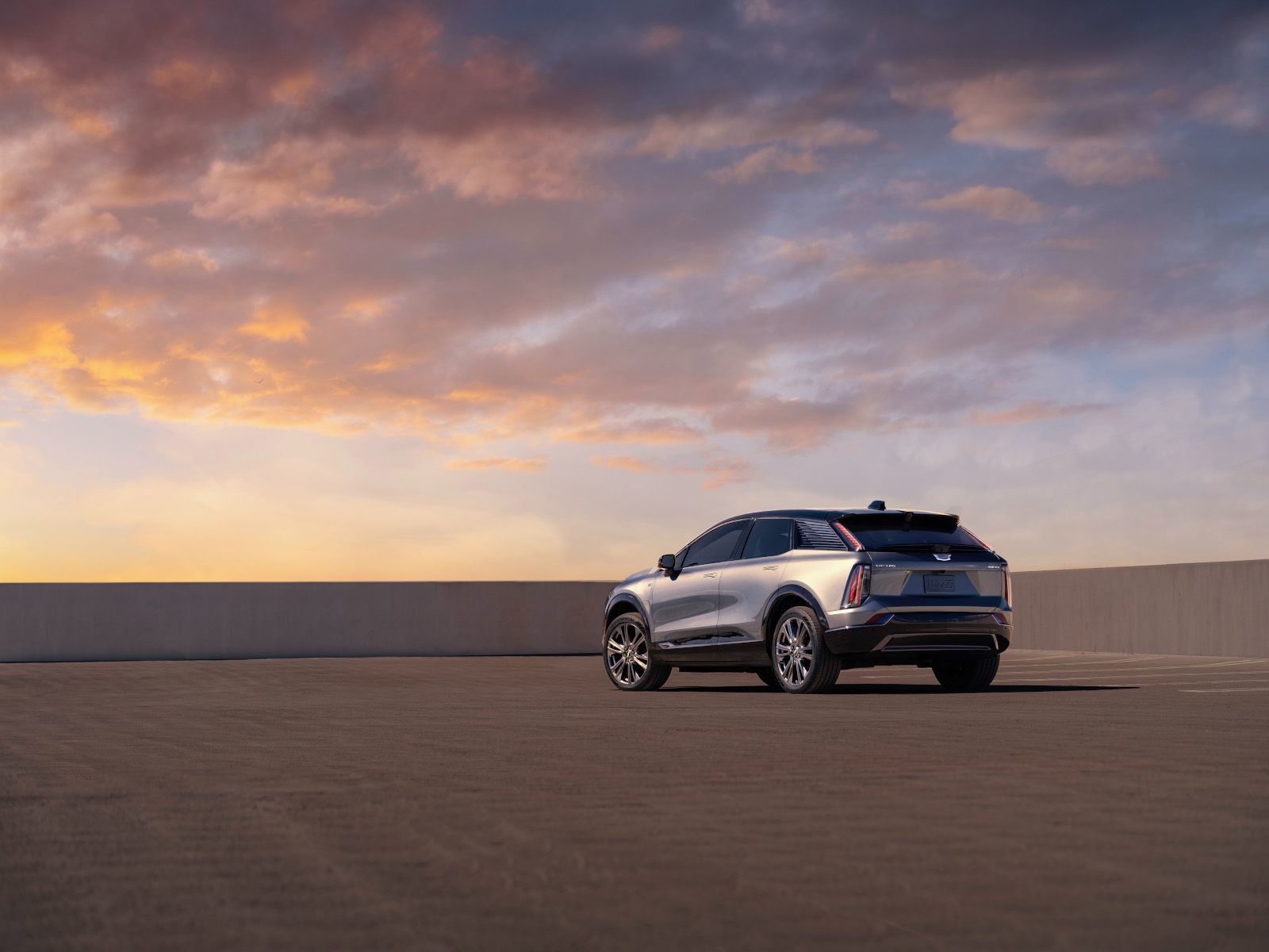 2026 Cadillac Optiq - rear view of a silver Cadillac Optiq parked on an open rooftop at sunset - City Chevrolet, Buick, GMC - New car dealership in Toronto, Ontario
