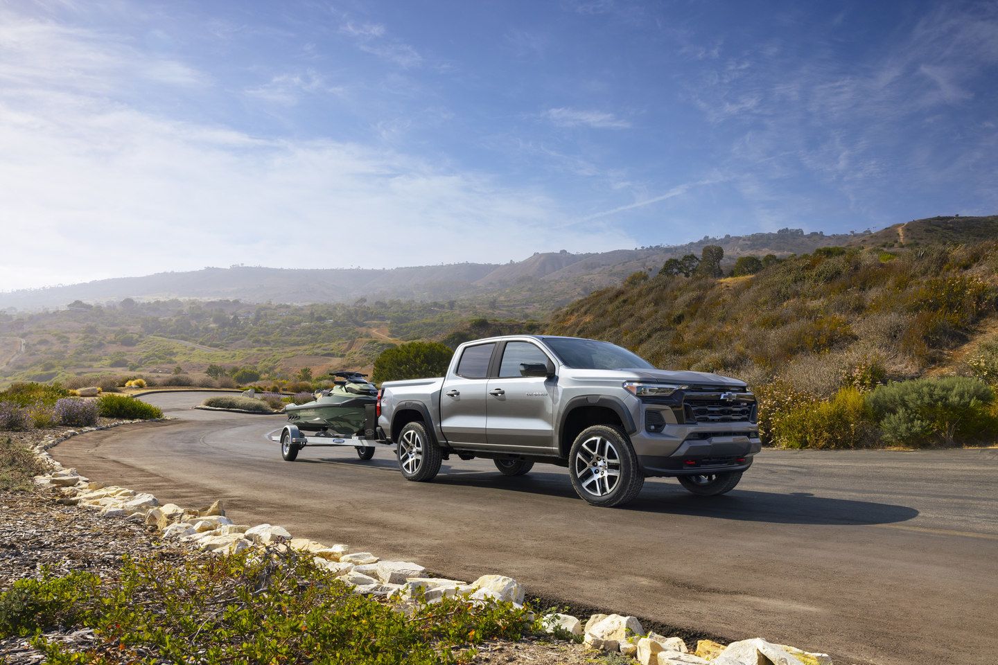 2026 Chevrolet Colorado - a silver 2026 Chevrolet Colorado towing a jet ski on a trailer along a coastal road - Applewood Chevrolet, Buick, GMC - Chevrolet new car dealership in Mississauga, Ontario