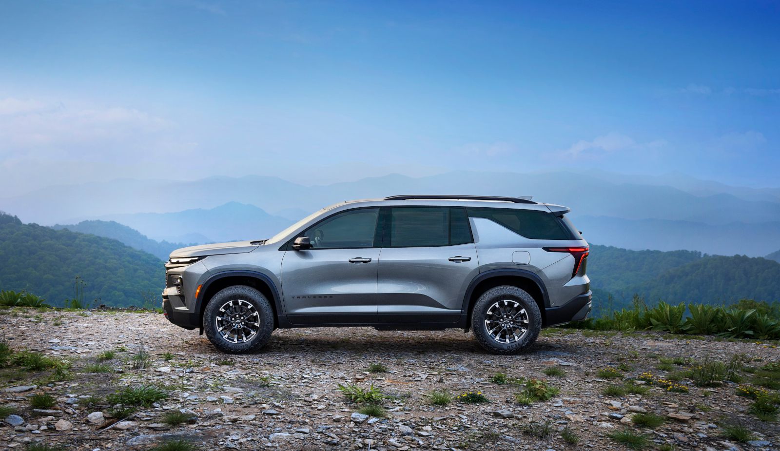 2026 Chevrolet Traverse - side profile view of a silver 2026 Chevrolet Traverse parked on a rocky overlook with a mountain backdrop - Applewood Chevrolet, Buick, GMC - Chevrolet new car dealership in Mississauga, Ontario