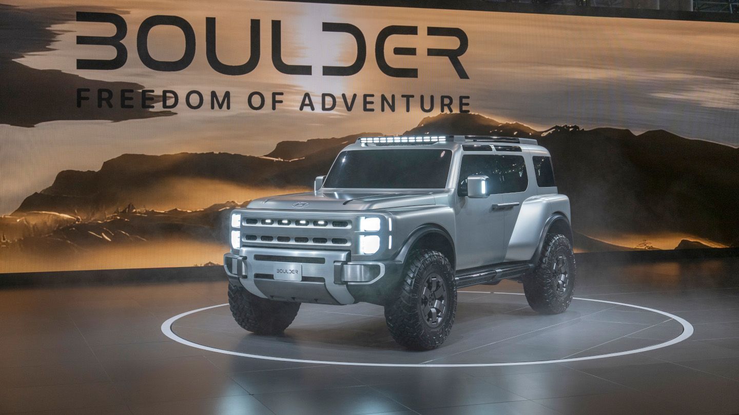 Hyundai Boulder - front-quarter view of the silver 2026 Hyundai Boulder showing the LED headlights on an auto show stage - Woodstock Hyundai - New car dealership in Woodstock, Ontario