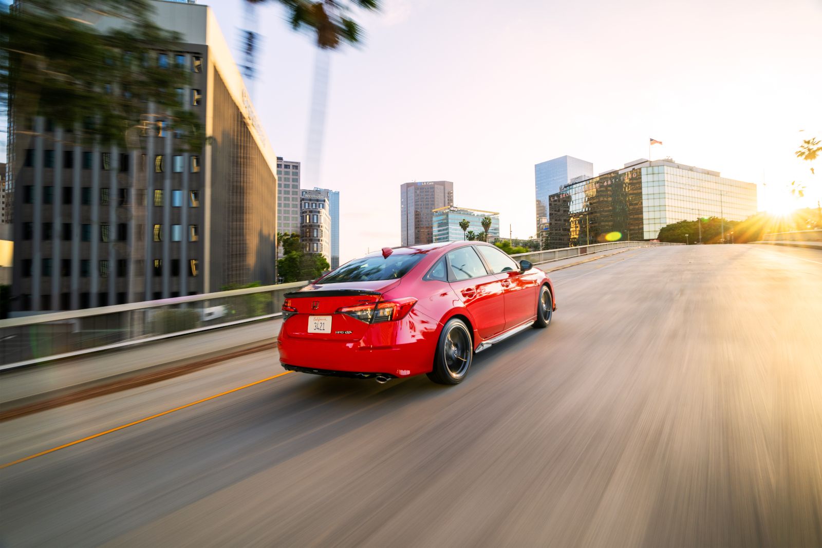 2026 Honda Civic Sedan Sport with HPD Package - rear view of a red 2026 Honda Civic Sedan Sport with HPD Package driving on a city highway - Goderich Honda - Honda new car dealership in Goderich, Ontario