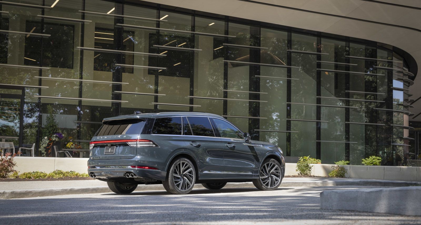 2026 Lincoln Aviator - rear profile view of a green 2026 Lincoln Aviator Black Label parked in front of a modern glass building - Bayfield Lincoln - New car dealership in Barrie, Ontario