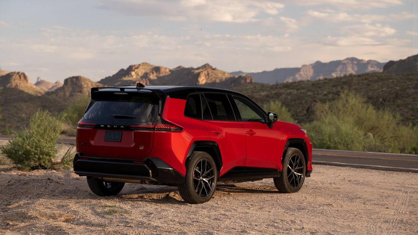 2026 Toyota RAV4 PHEV - Rear three-quarter view of a red 2026 Toyota RAV4 PHEV GR Sport parked on a dirt shoulder in a desert mountain landscape - Orangeville Toyota - New car dealership in Orangeville, Ontario