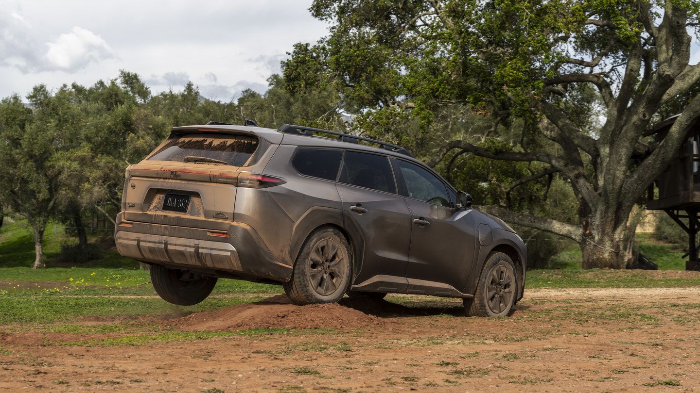 2026 Toyota bZ Woodland - Rear view of a muddy bronze 2026 Toyota bZ Woodland Premium driving over a dirt mound - Oakville Toyota - New car dealership in Oakville, Ontario