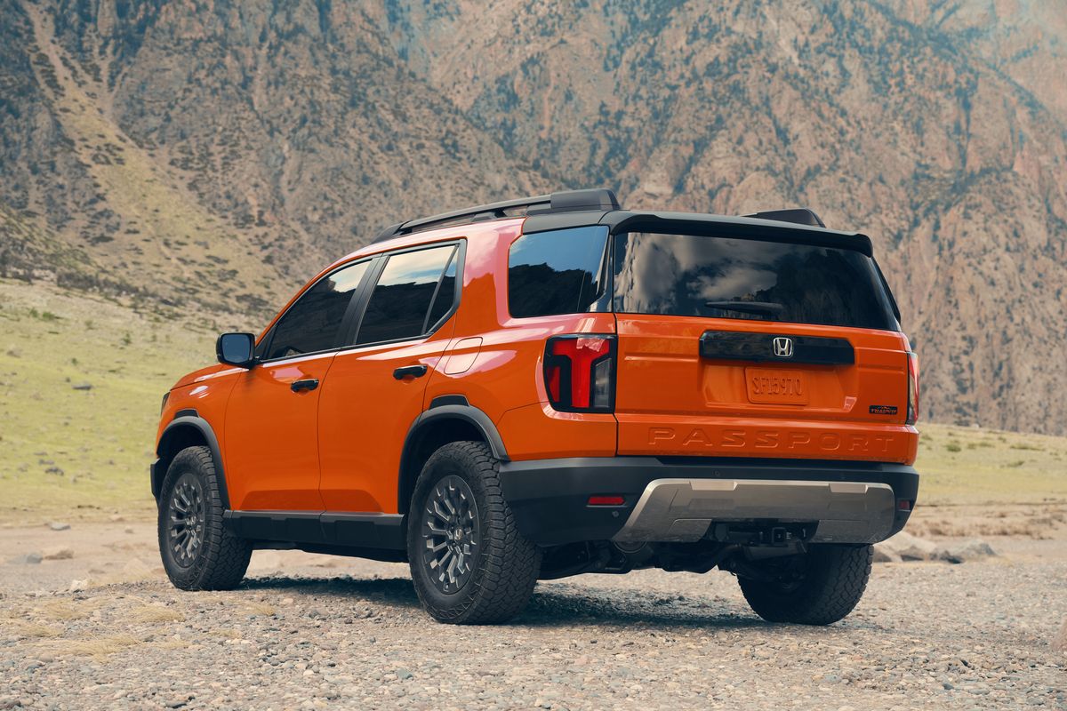 2026 Honda Passport TrailSport - Rear three-quarter view of an orange 2026 Honda Passport TrailSport parked on a rocky desert trail - Orangeville Honda - New car dealership in Orangeville, Ontario