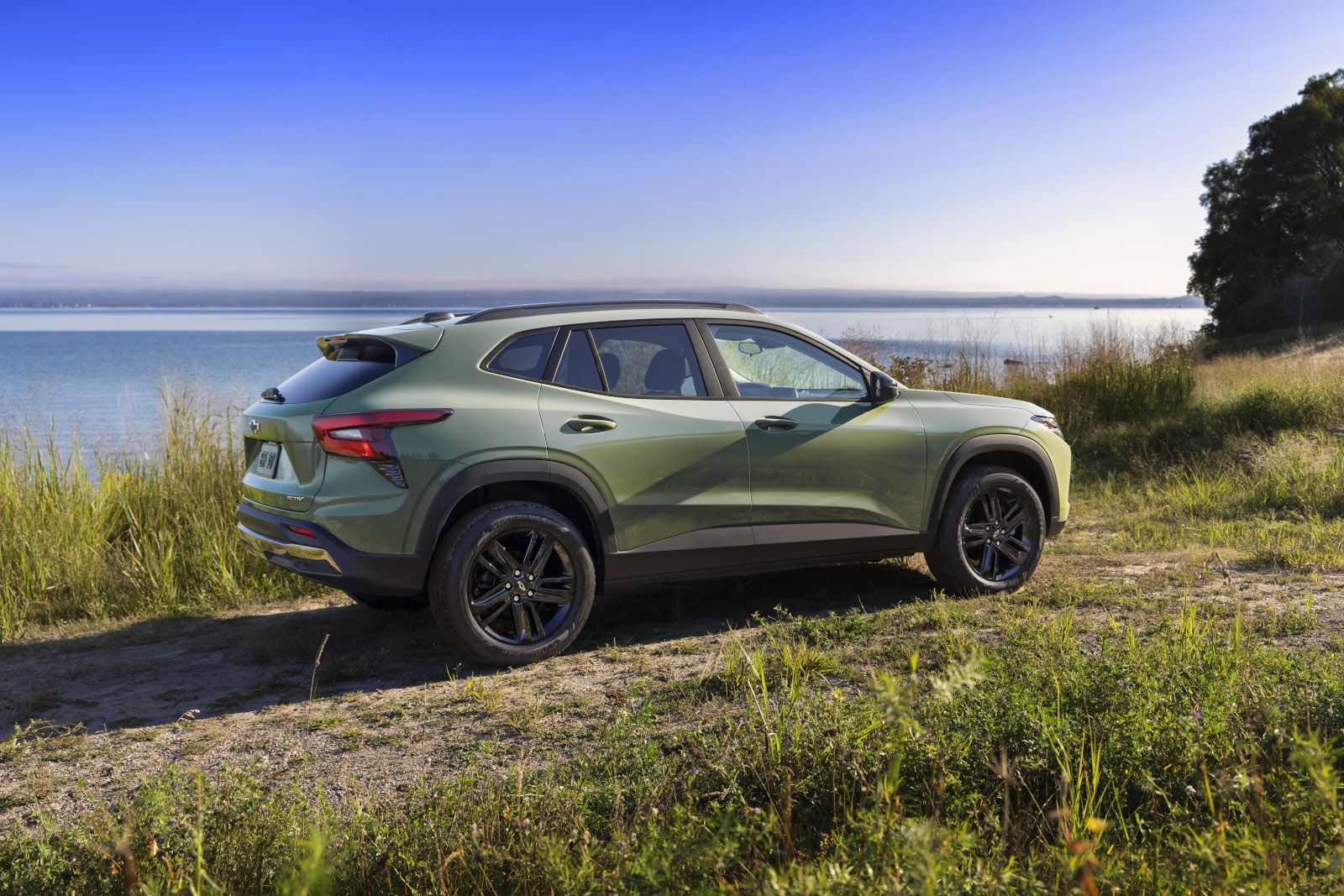 2026 Chevrolet Trax - Side profile view of a green Chevrolet Trax parked on a grassy trail next to the water - Applewood Chevrolet, Buick, GMC - New car dealership in Mississauga, Ontario