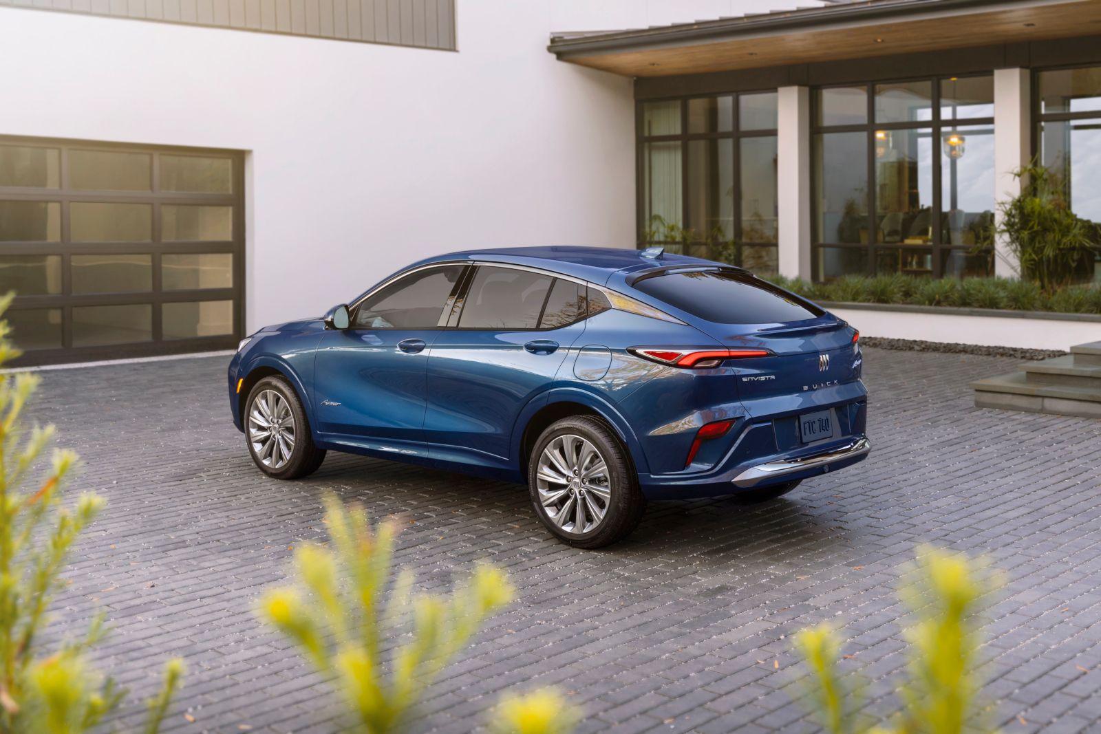 2026 Buick Envista Avenir - Rear three-quarter view of a metallic blue 2026 Buick Envista Avenir parked on a brick driveway in front of a modern home - City Chevrolet, Buick, GMC - New car dealership in Toronto, Ontario