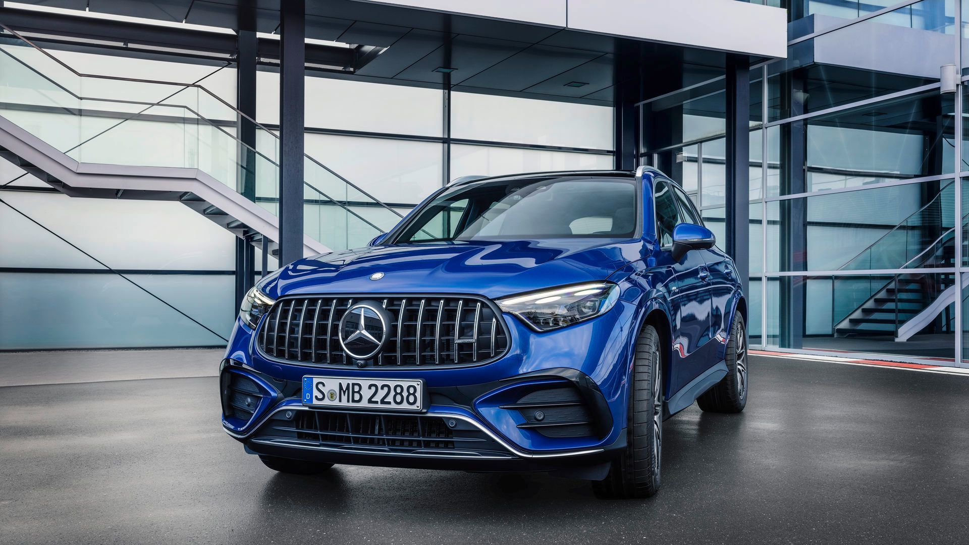 2026 Mercedes-AMG GLC 43 - Front view of a blue 2026 Mercedes-AMG GLC 43 SUV showcasing the Panamericana grille outside a modern building - Mercedes-Benz Brampton - New car dealership in Brampton, Ontario