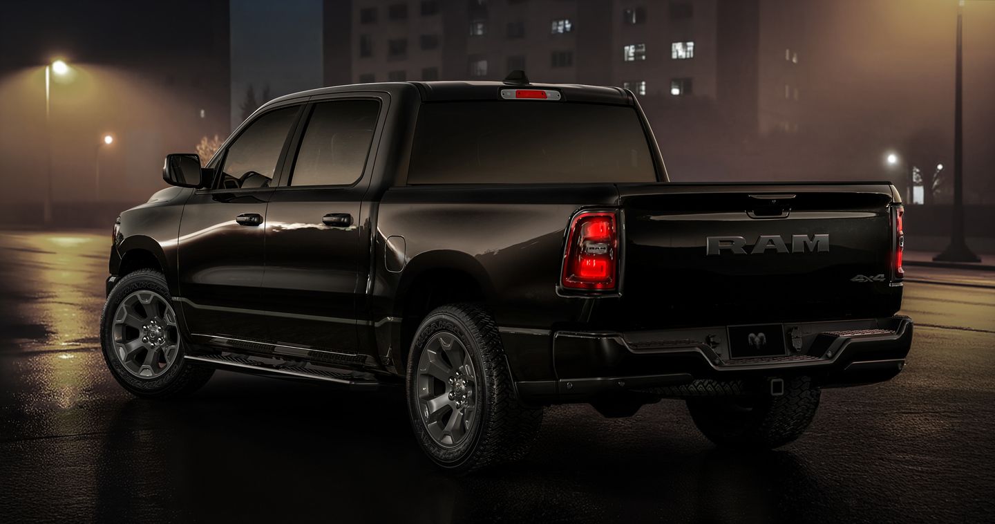 2026 Ram 1500 - rear three-quarter view of a black 2026 Ram 1500 pickup truck showcasing the tailgate and taillights on a wet road at night - Cooksville Dodge - New car dealership in Mississauga, Ontario