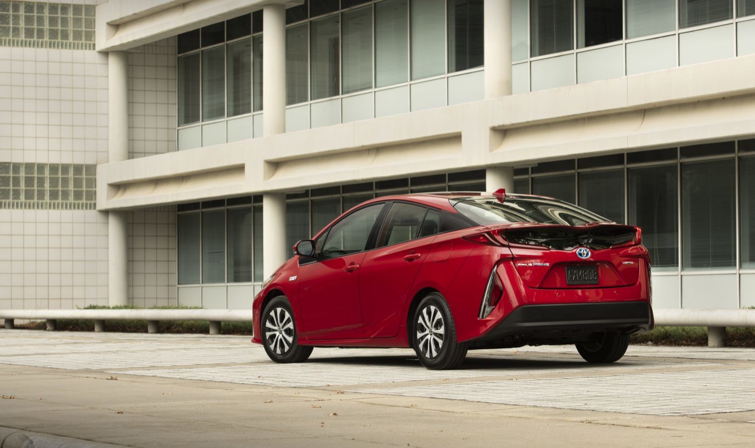 Toyota Prius - Rear three-quarter view of a red Toyota Prius parked on a concrete plaza - AutoPark Barrie - New car dealership in Barrie, Ontario