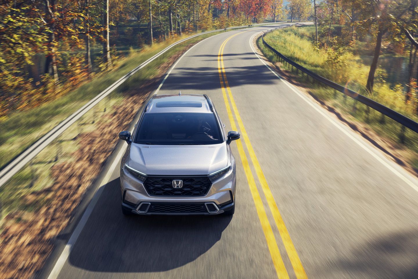 Honda CR-V - Overhead front view of a silver Honda CR-V driving down a winding tree-lined road - AutoPark Barrie - New car dealership in Barrie, Ontario