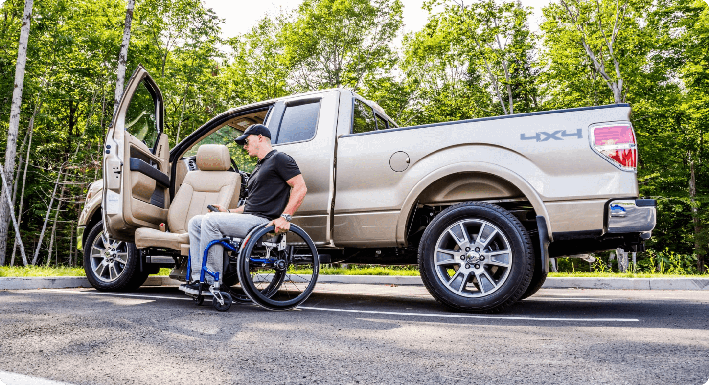 Ford F-150 - Side profile view of a man in a wheelchair using a specialized exterior power lift system to exit a tan Ford F-150 pickup truck - Humberview Mobility - Accessible car dealership in Toronto, Ontario