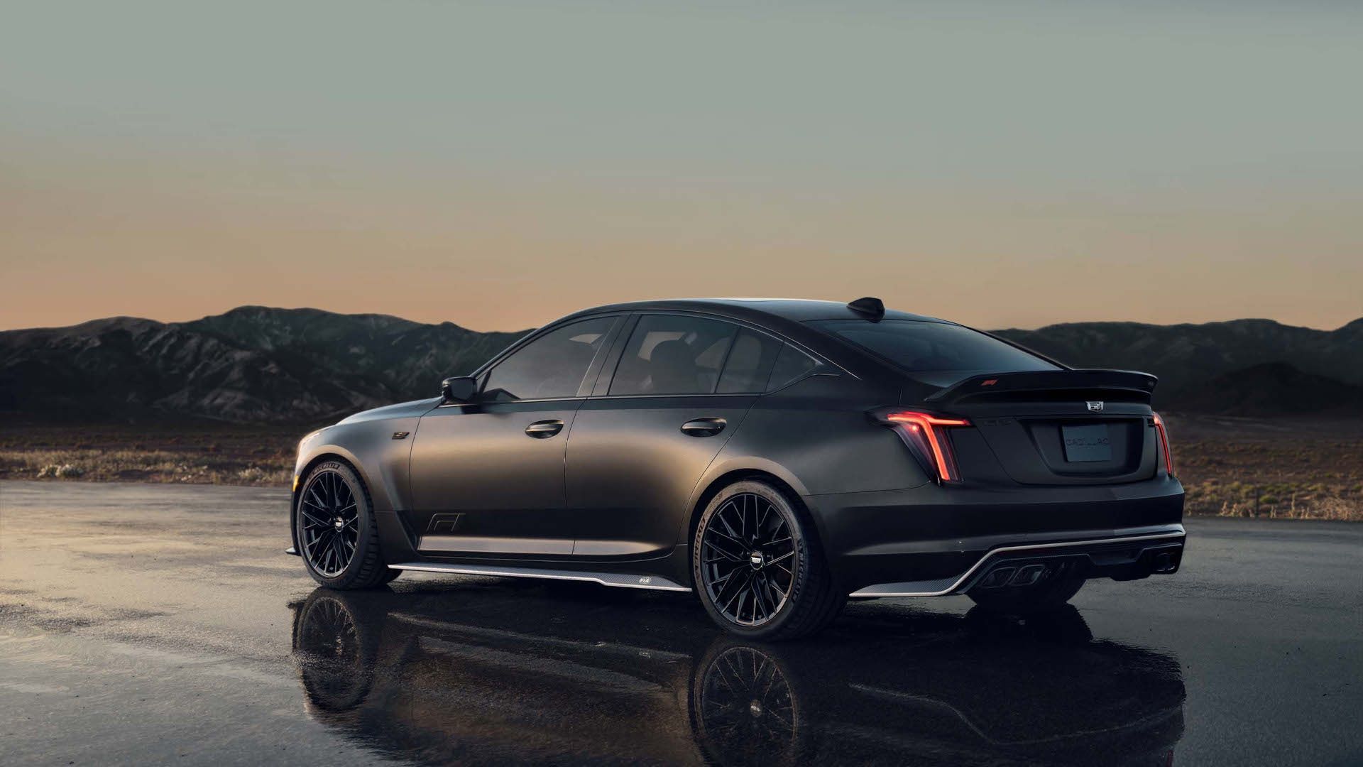 2026 Cadillac CT5-V Blackwing - Rear three-quarter view of a matte black 2026 Cadillac CT5-V Blackwing F1 Collector Series parked on a wet surface at sunset - Applewood Cadillac - Cadillac new car dealership in Mississauga, Ontario