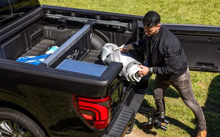 2026 Ford F-150 - A man loading gear into the truck bed of a 2026 Ford F-150 through the Pro-Access Tailgate opening - Bayfield Ford - New car dealership in Barrie, Ontario
