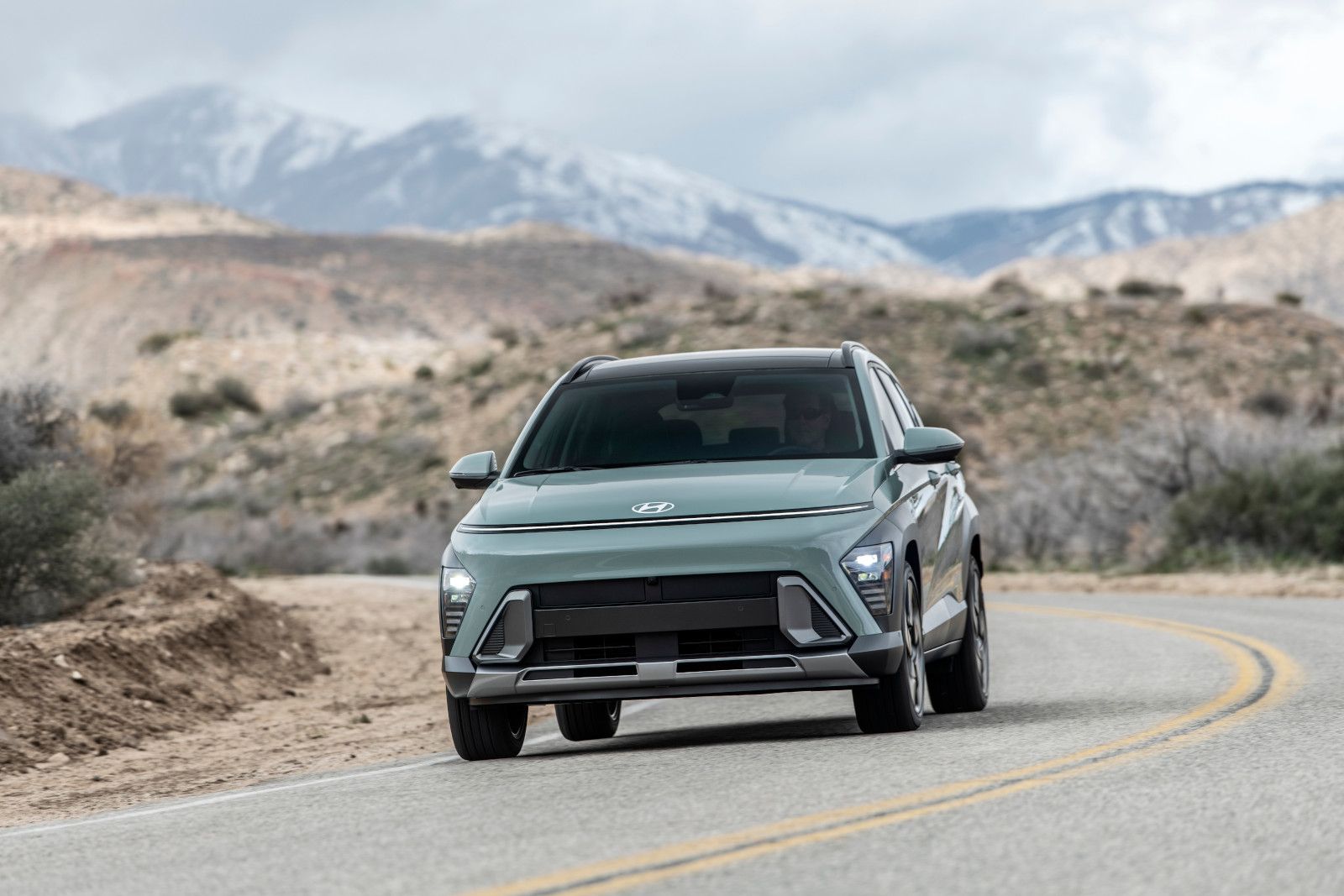 2026 Hyundai Kona - Front view of a green Hyundai Kona driving on a winding road - Woodstock Hyundai - New car dealership in Woodstock, Ontario