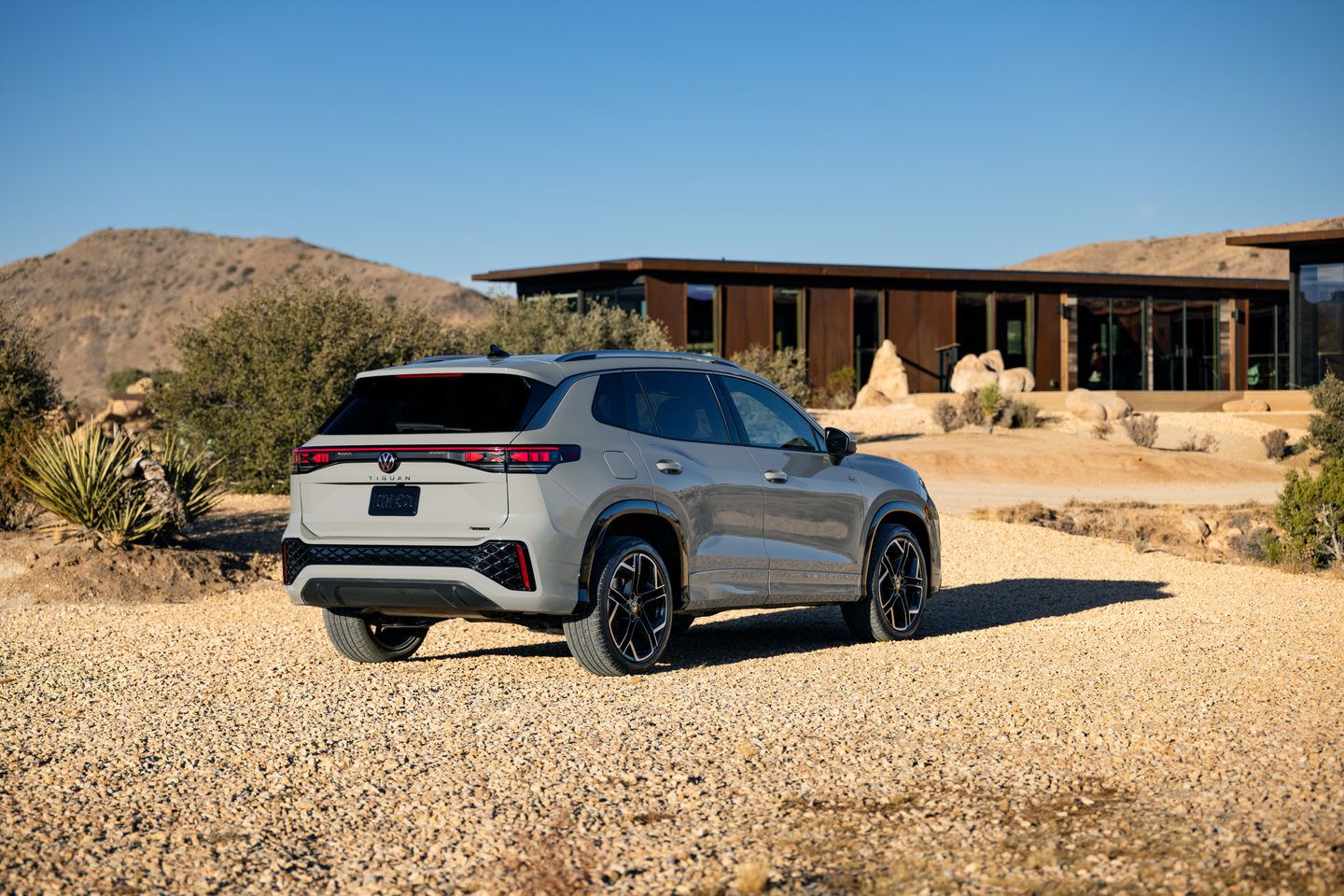 2026 Volkswagen Tiguan - Rear driver-side view of an Ascot Grey 2026 Volkswagen Tiguan R-Line parked on gravel - Volkswagen MidTown - New car dealership in Toronto, Ontario