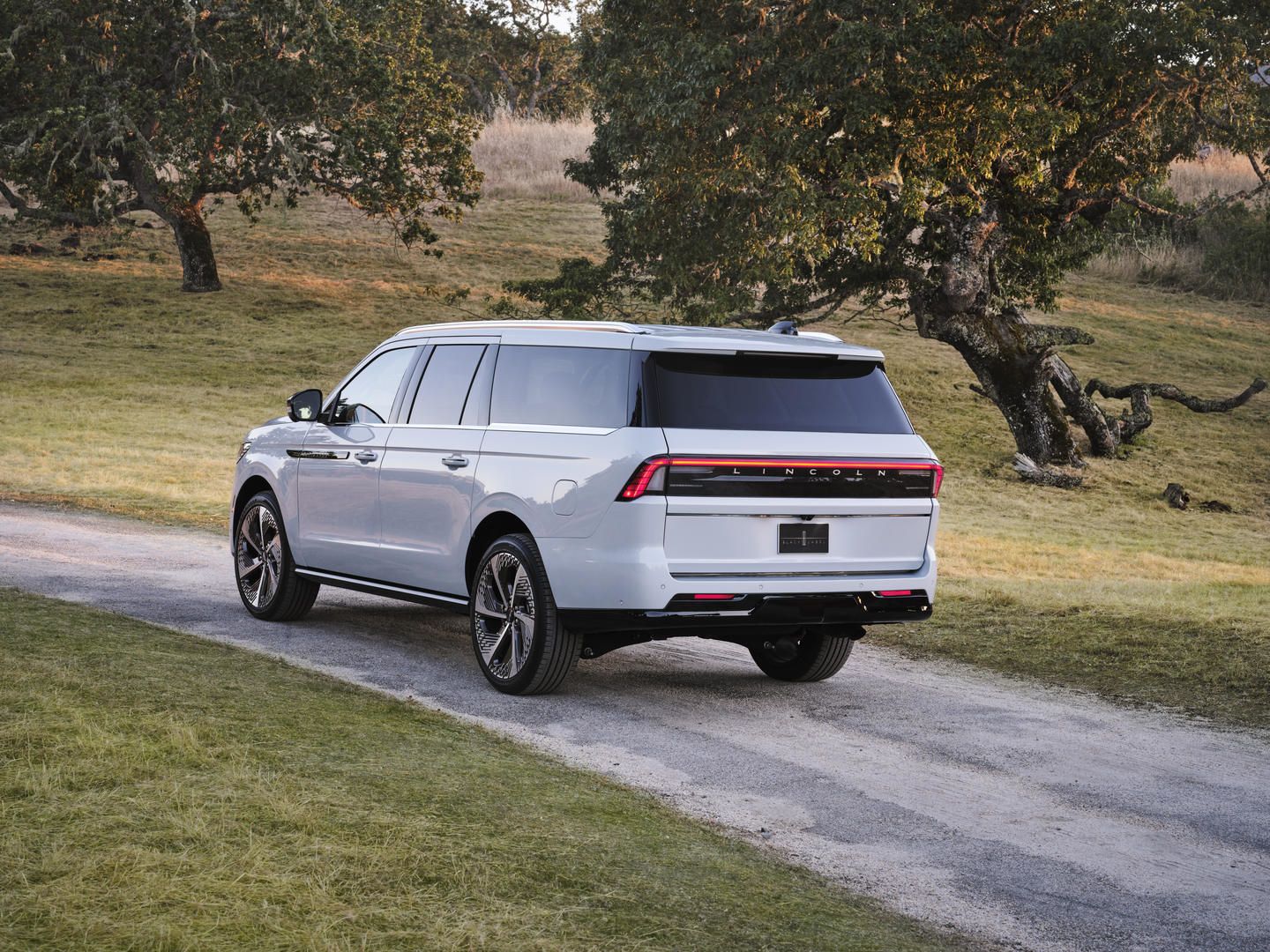 2026 Lincoln Navigator - Rear three-quarter view of a crystal white 2026 Lincoln Navigator L parked on a dirt road near trees - Mayfield Lincoln - Lincoln car dealership in Brampton, Ontario