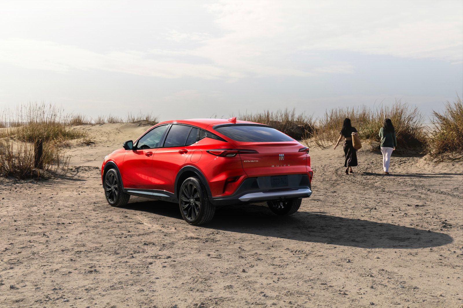 2026 Buick Envista - rear view of a red 2026 Buick Envista ST on a sandy beach with people walking - City Chevrolet, Buick, GMC - Buick car dealership in Toronto, ON