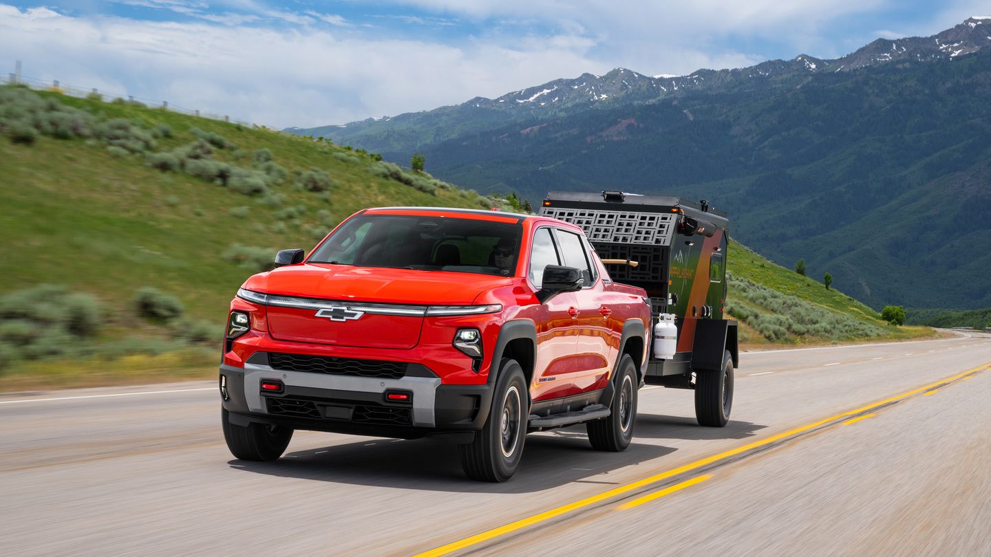 2026 Chevrolet Silverado EV Trail Boss - Front driver side view of a red 2026 Chevrolet Silverado EV Trail Boss driving on a highway while towing a trailer - Humberview Chevrolet, Buick, GMC - New car dealership in Toronto, Ontario