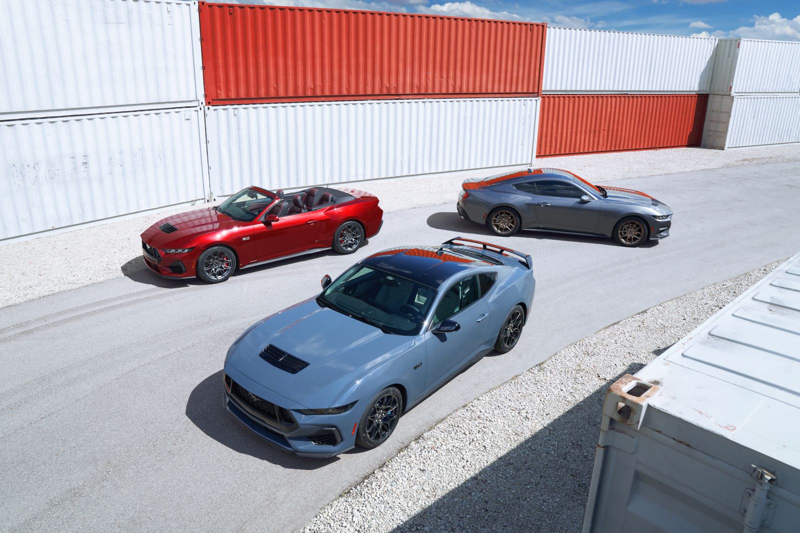 2026 Ford Mustang - three Ford Mustangs in a group: one red, one grey, one blue, parked in a lot - Bayfield Ford - Ford car dealership in Barrie, ON