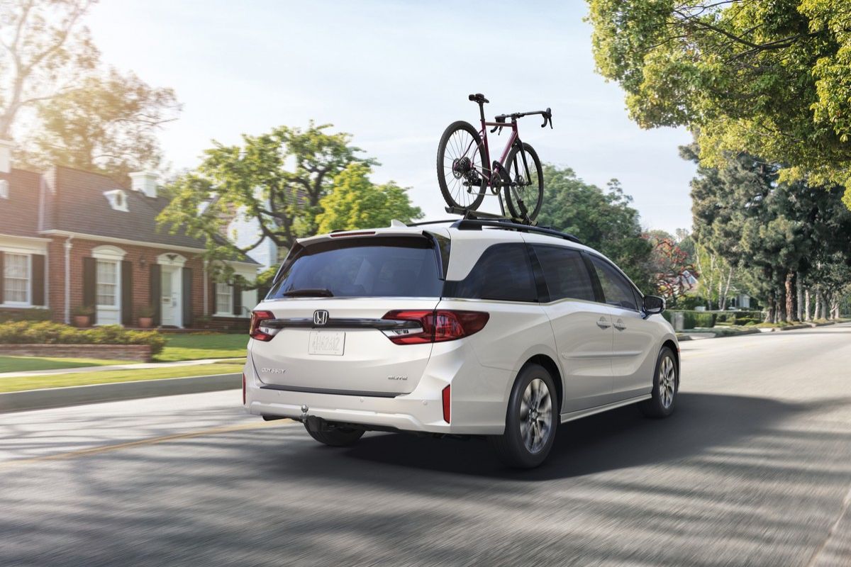2026 Honda Odyssey - rear view of a white 2026 Honda Odyssey driving on a street with a bicycle mounted on the roof rack - Orangeville Honda - New car dealership in Orangeville, Ontario